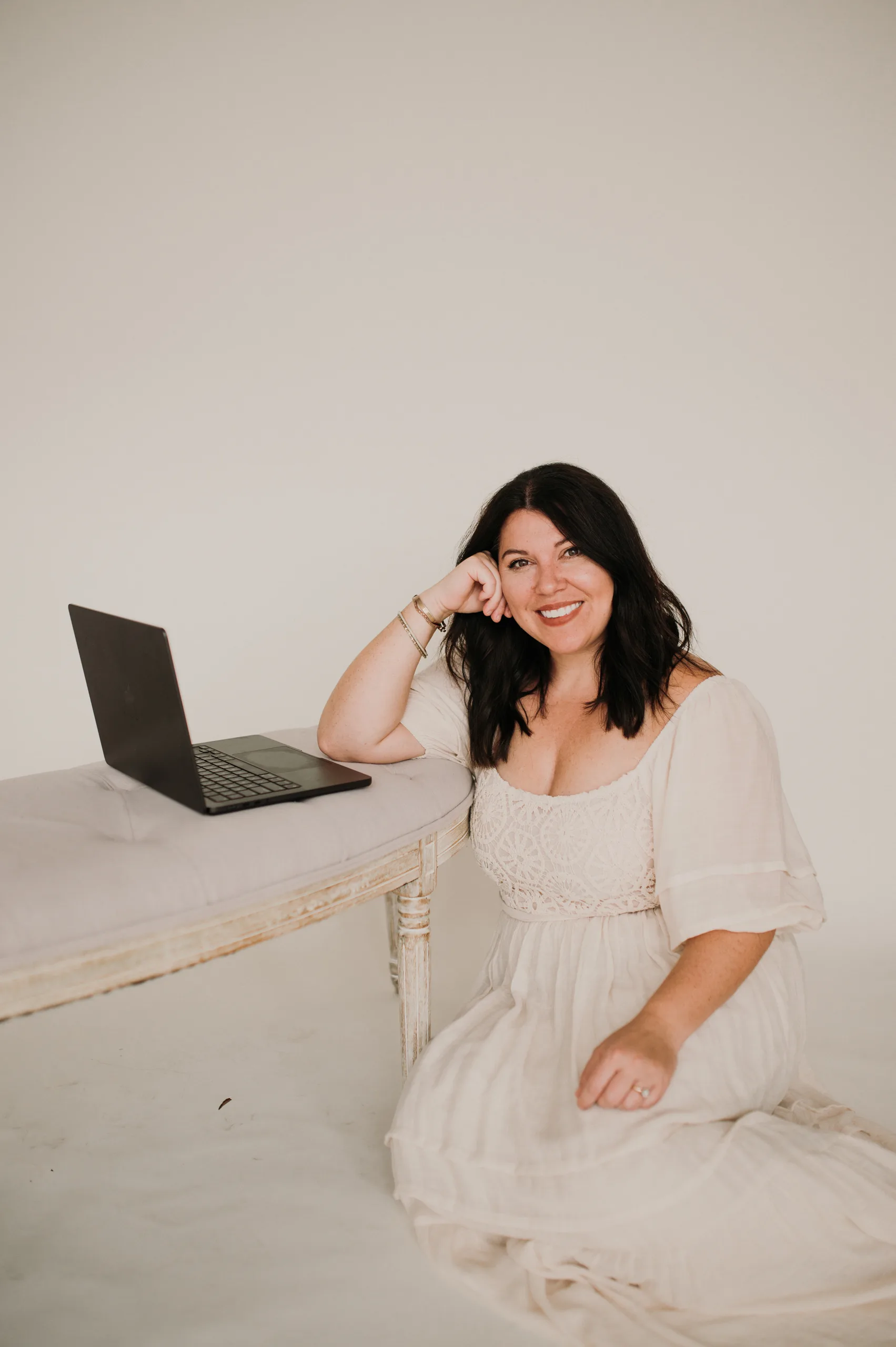 Woman sitting beside an open laptop in a bright minimalist studio. — how to drive more traffic to your website